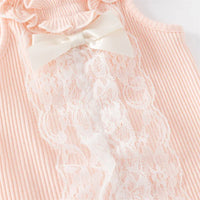 Close-up of pink ruffle knit baby romper with white lace and satin bow detail for infants