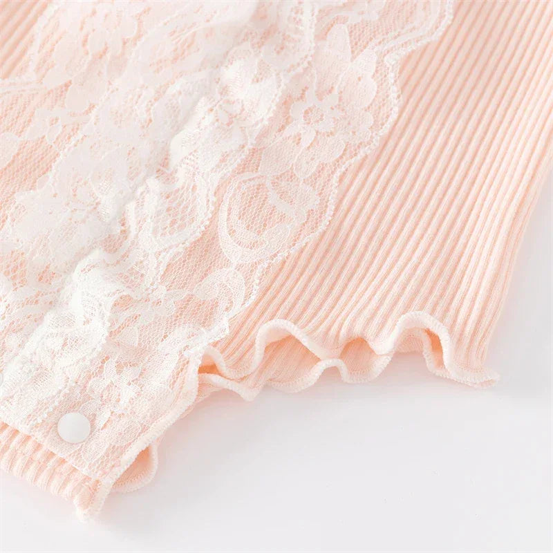 close-up of peach ruffle knit baby romper with white lace detail for infants
