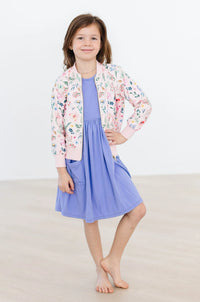 Girls pink floral satin jacket with ribbed cuffs and collar over blue dress