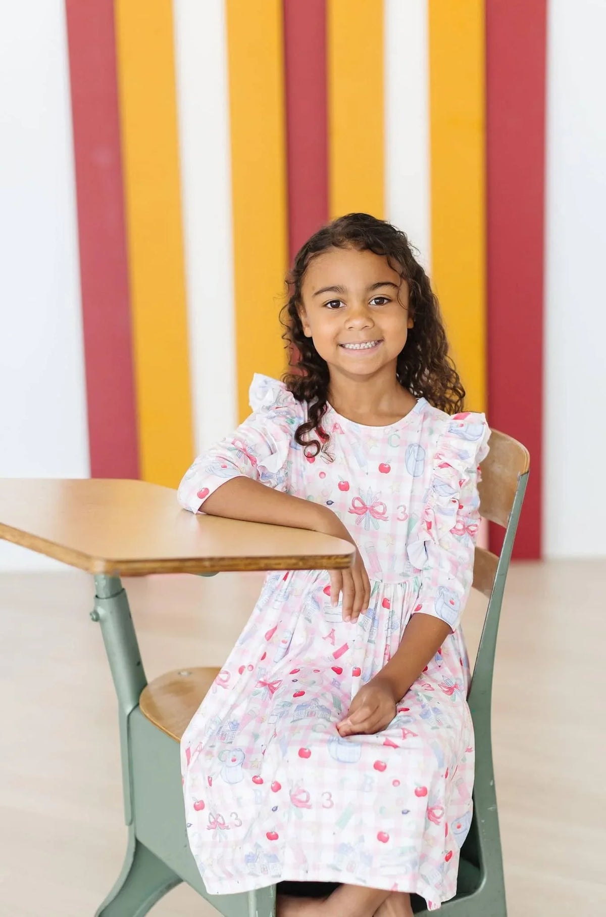 Girls pink and white school days girls ruffle dress with 3/4 sleeves seated at school desk