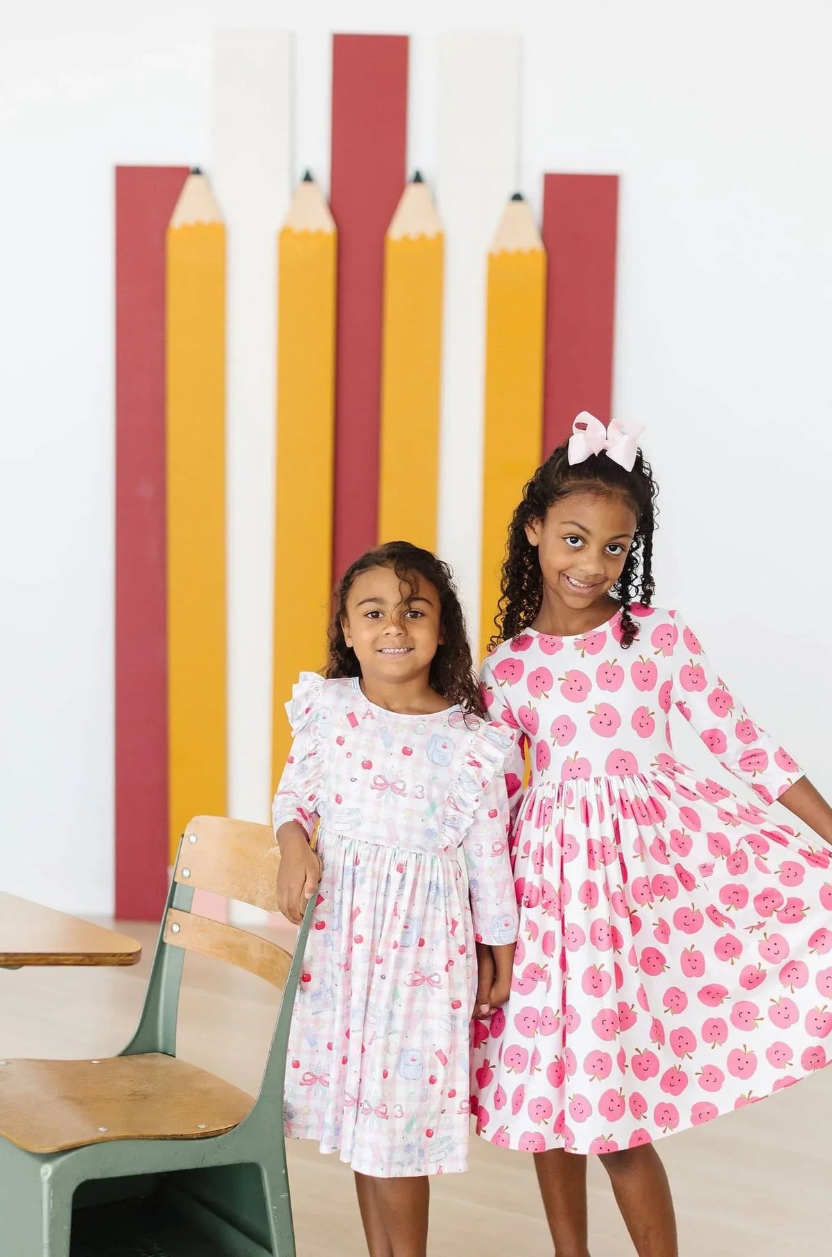 Two girls wearing school days girls ruffle dress by Mila & Rose, pink and white long sleeve with twirl skirts