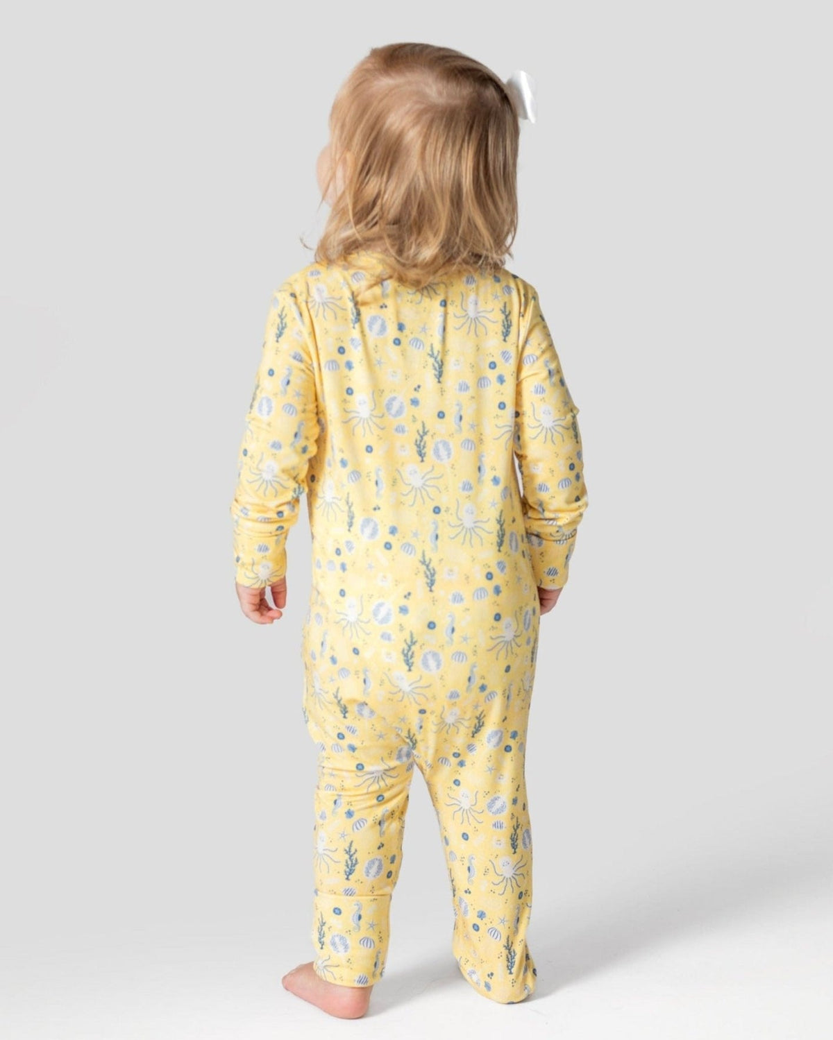 Toddler wearing yellow sea creature print bamboo romper featuring octopus and seashell patterns for breathable comfort.