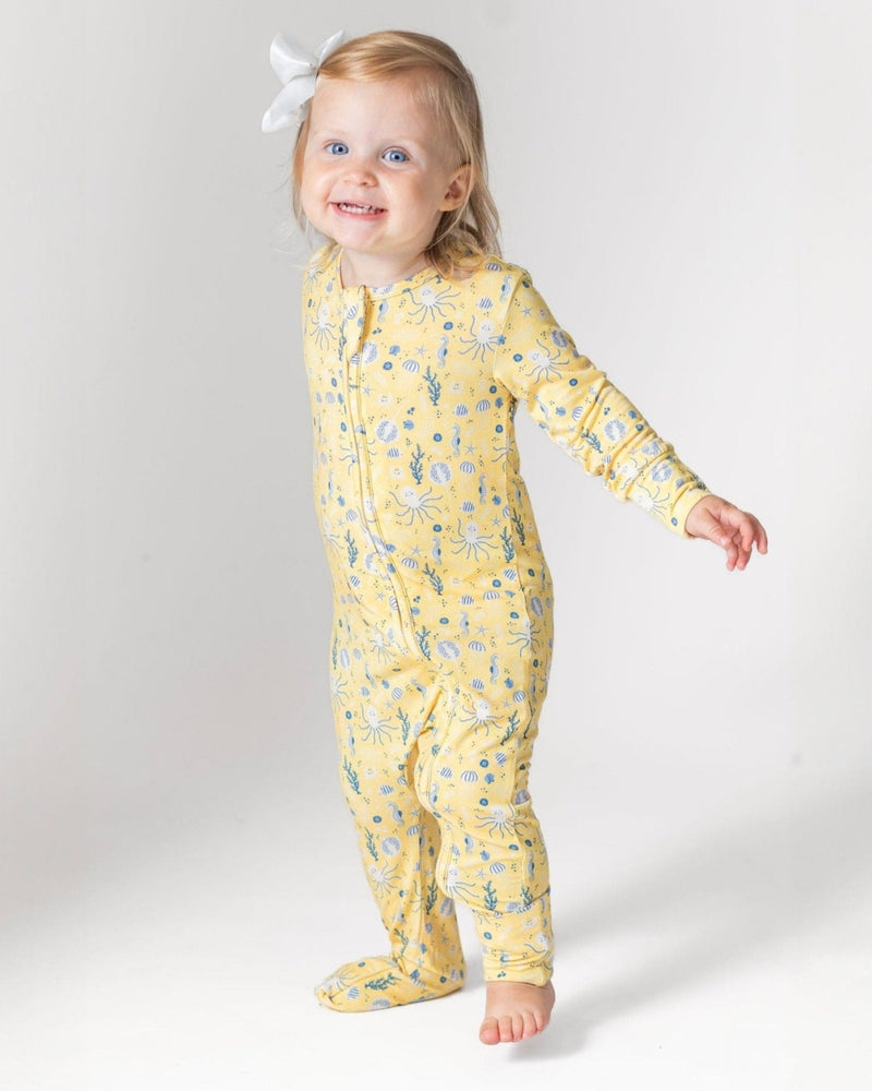 Toddler wearing yellow sea creature print bamboo romper with octopus and seahorse pattern, featuring footies and ultra-soft comfort.