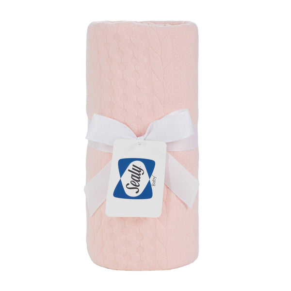 Sealy baby knit blanket apricot rose color made of soft knitted fabric with a white ribbon tied around it