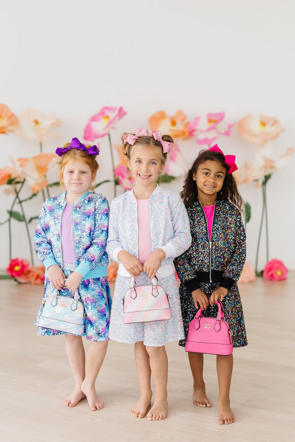 Three girls wearing colorful sequin jackets with matching skirts and holding handbags, long sleeve sequin jacket
