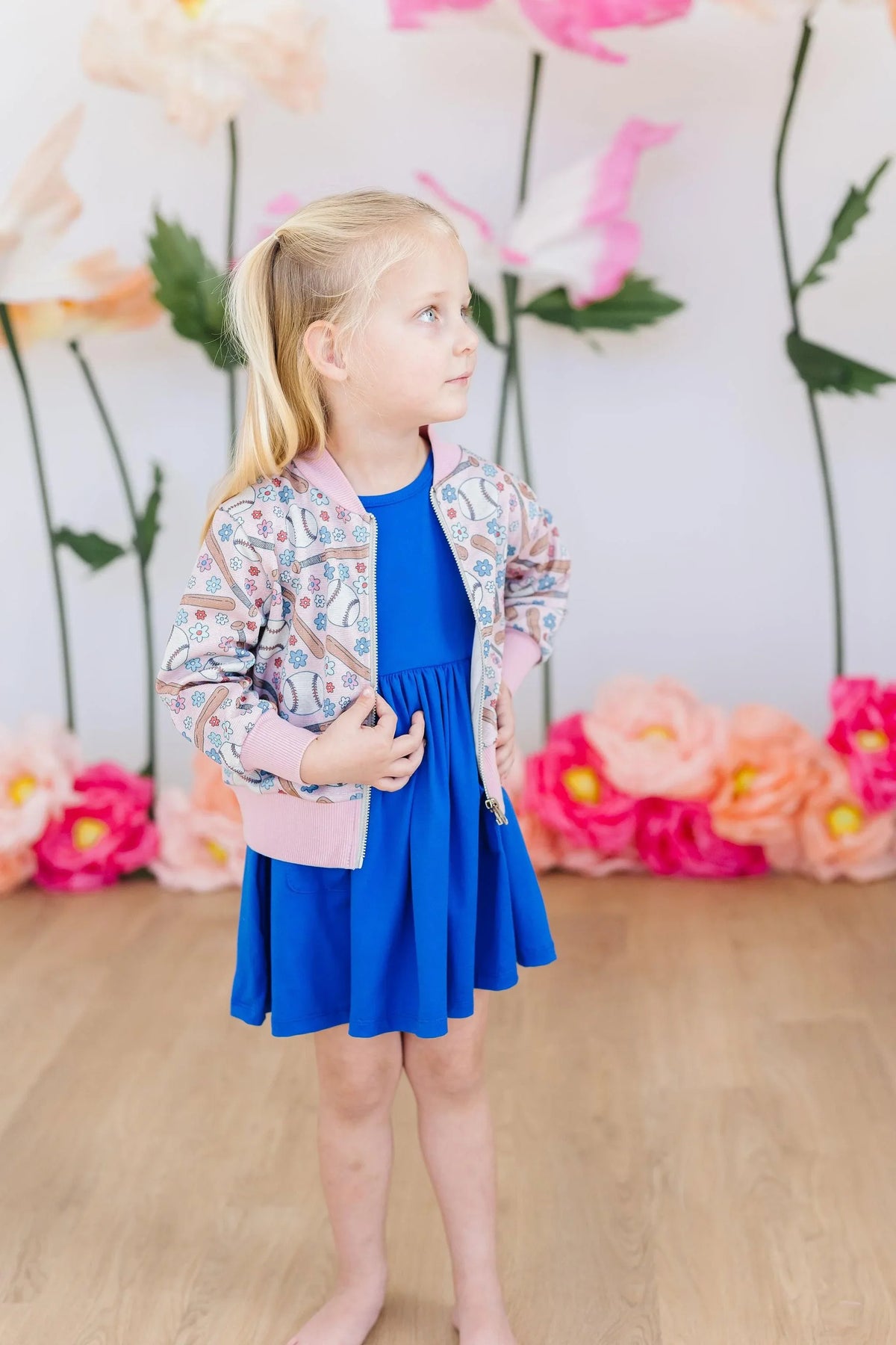 Girls pink patterned shimmer jacket with long sleeves worn over a blue dress