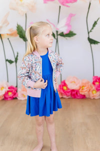 Girls pink patterned shimmer jacket with long sleeves worn over a blue dress