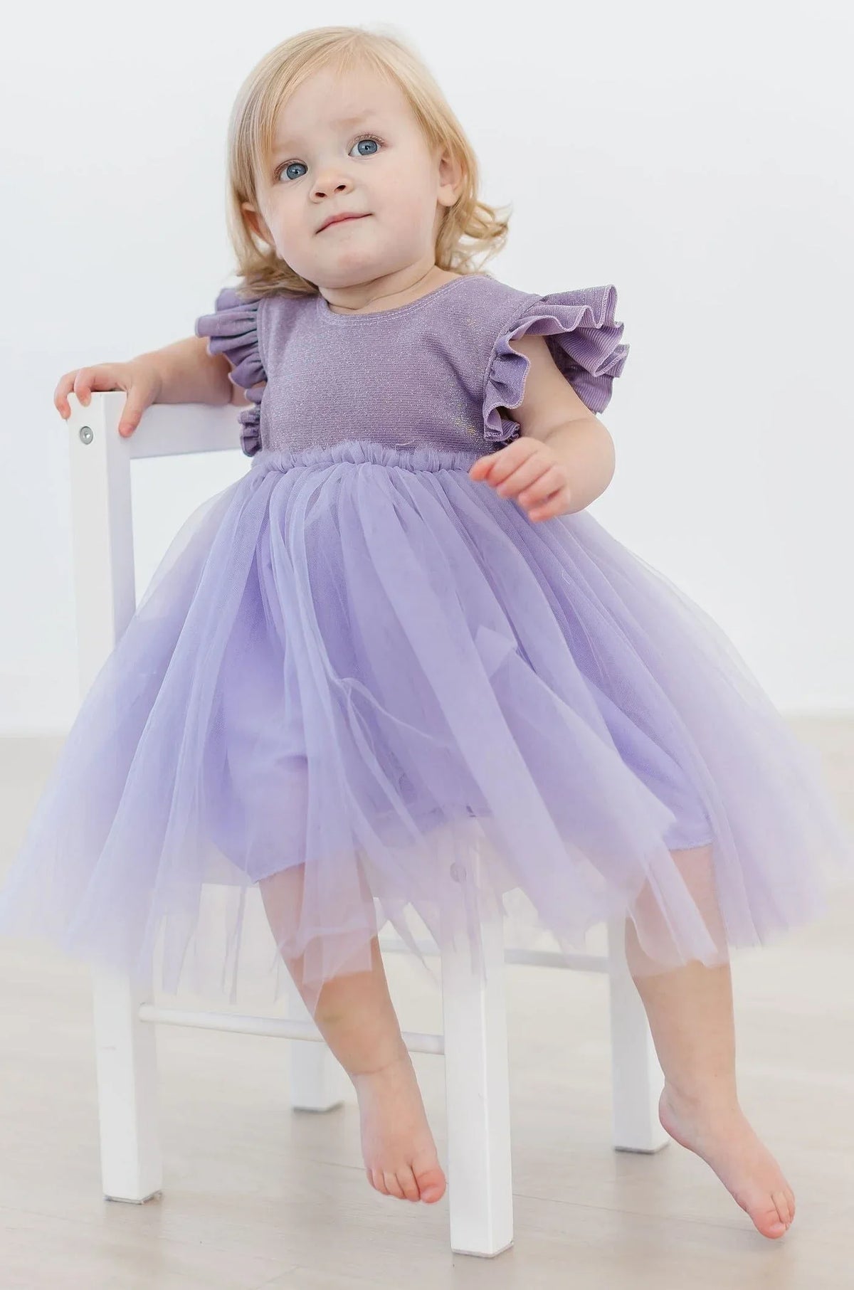 Toddler girl wearing lavender shimmer party dress for girls with ruffled sleeves and tulle tutu skirt