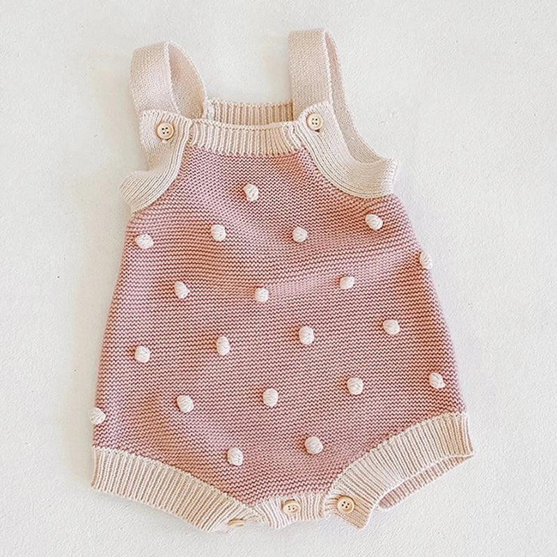 Pink and cream soft knit baby romper for babies with pom pom knit details and button straps