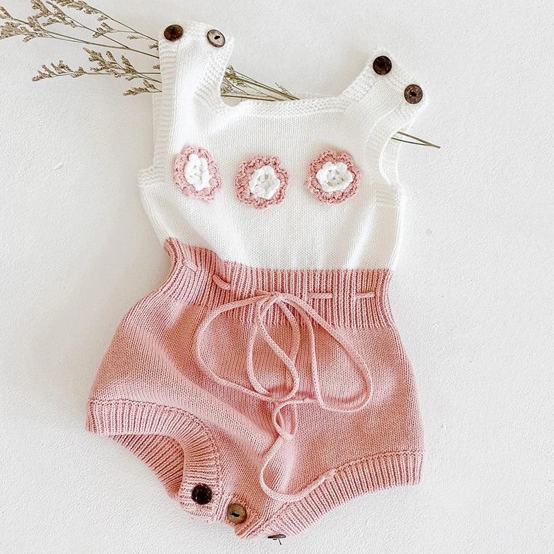 soft knit baby romper for girls in white and pink with floral details and button straps
