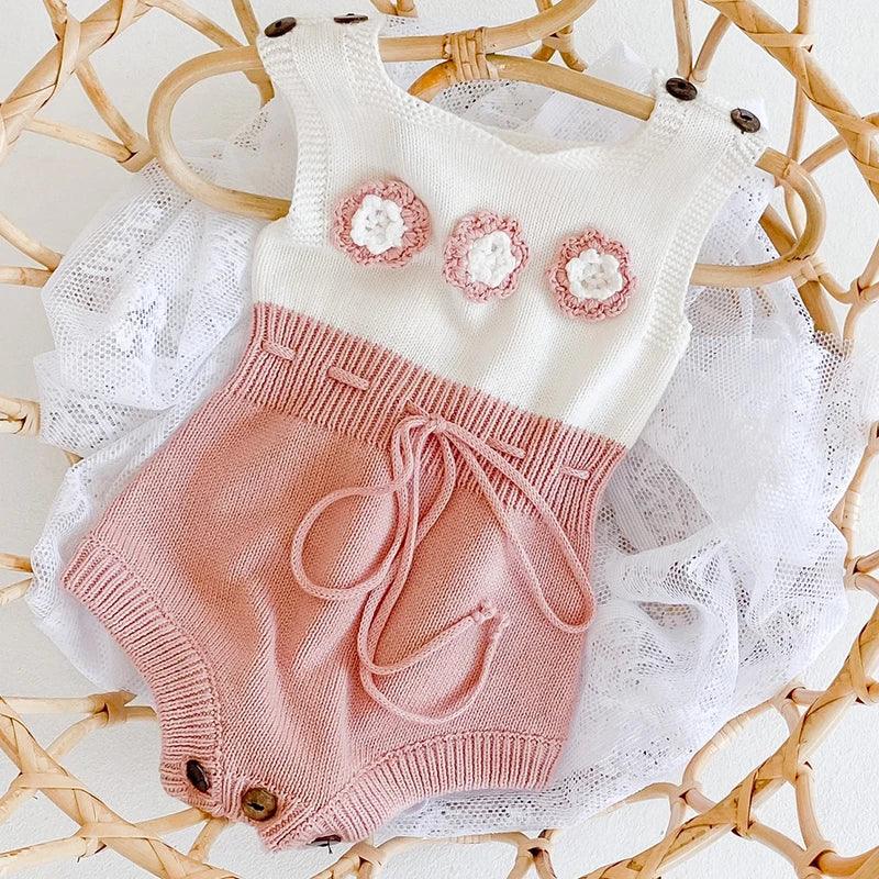 soft knit baby romper for infants in white and pink with floral details and button straps