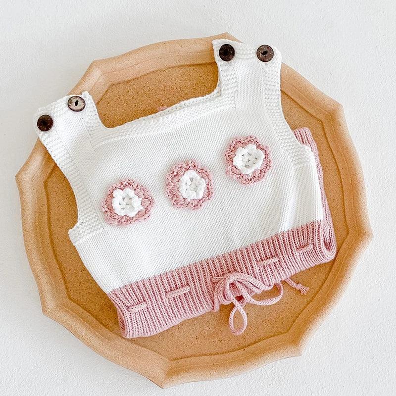 white and pink soft knit baby romper for babies with flower details and button straps