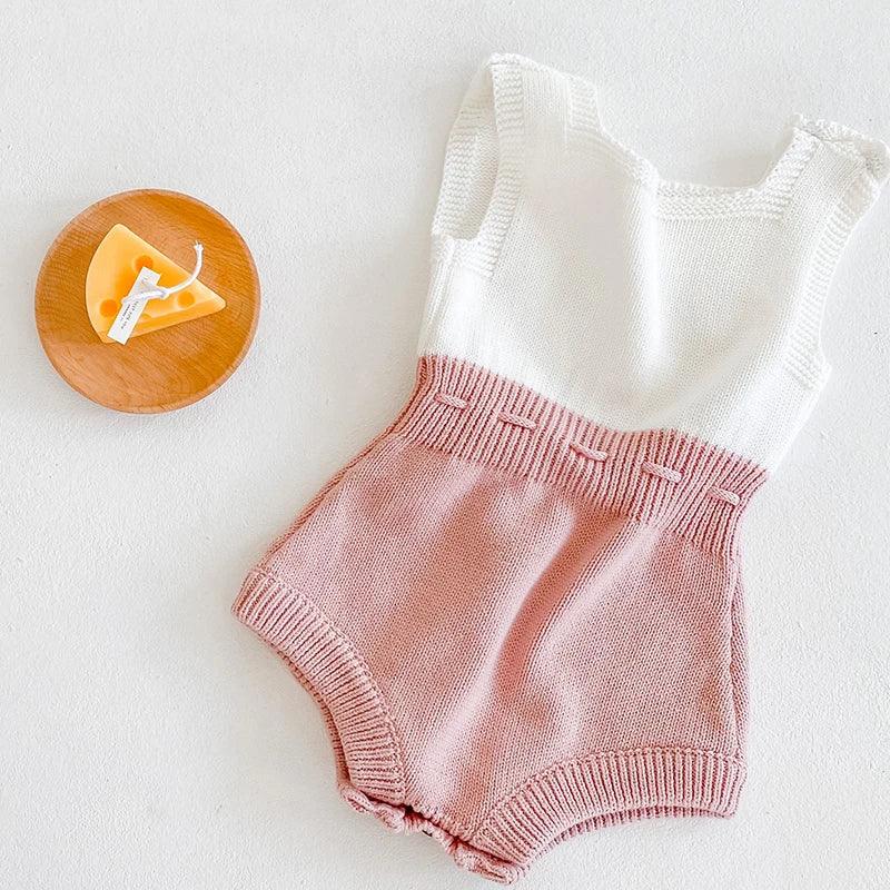 Soft knit baby romper in white and pink for infants with sleeveless design and ribbed waistband detail