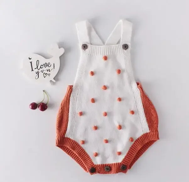 soft knit baby romper for infants with white and rust orange colors and textured pom pom details