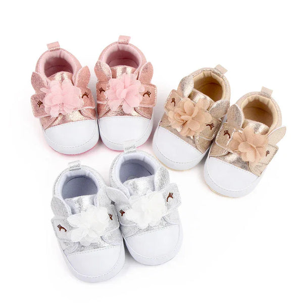 Three pairs of soft sole baby shoes in pink, beige, and silver with floral and bunny ear details