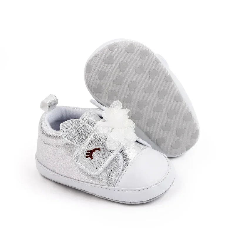 silver soft sole baby shoes with white flower and bunny ears for infants, one shoe upright and one showing sole