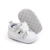 Silver soft sole baby shoes with white flower detail for infants, one shoe standing and one showing sole