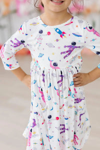 Girl wearing white space print twirl dress for girls with colorful astronaut and rocket designs posing with hands on hips