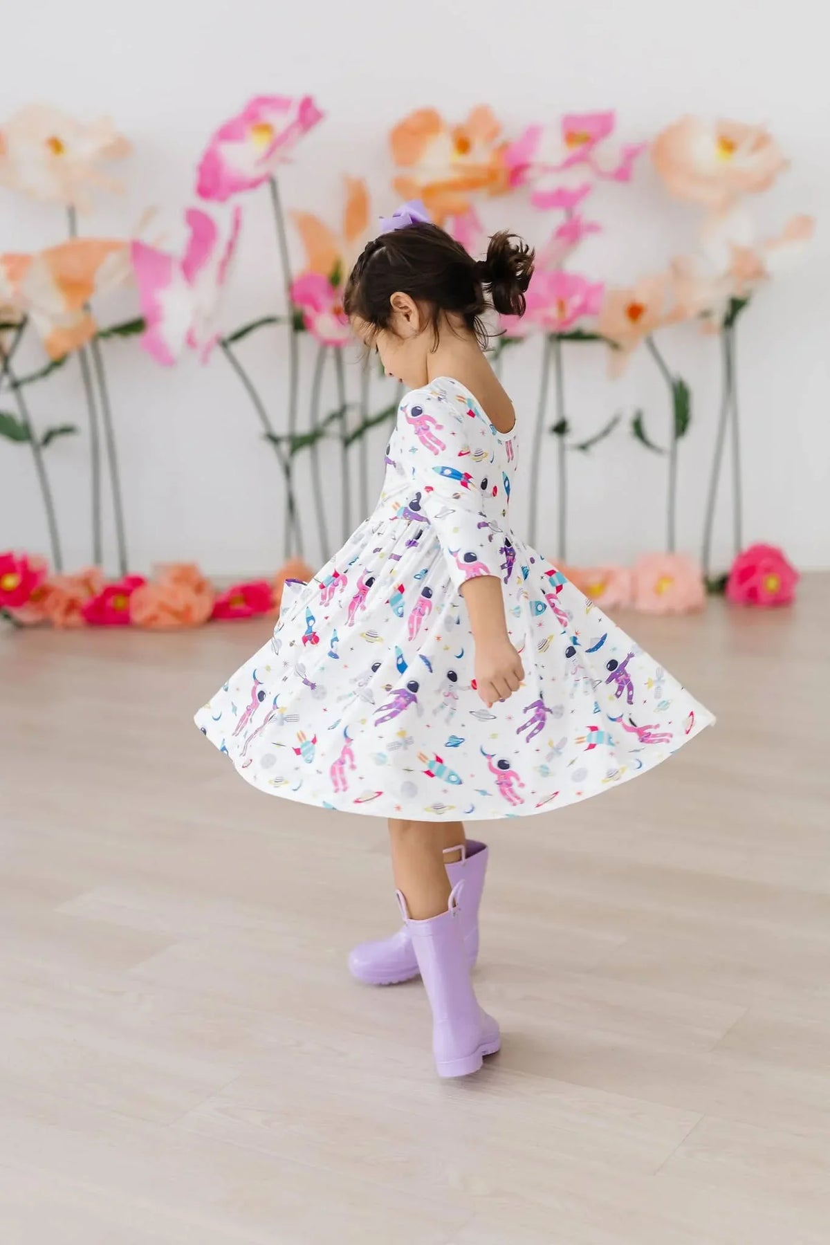 girl wearing white space print twirl dress for girls with 3/4 sleeves spinning indoors