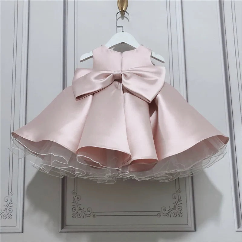 baby pink satin special occasion dress with large bow and tulle underskirt