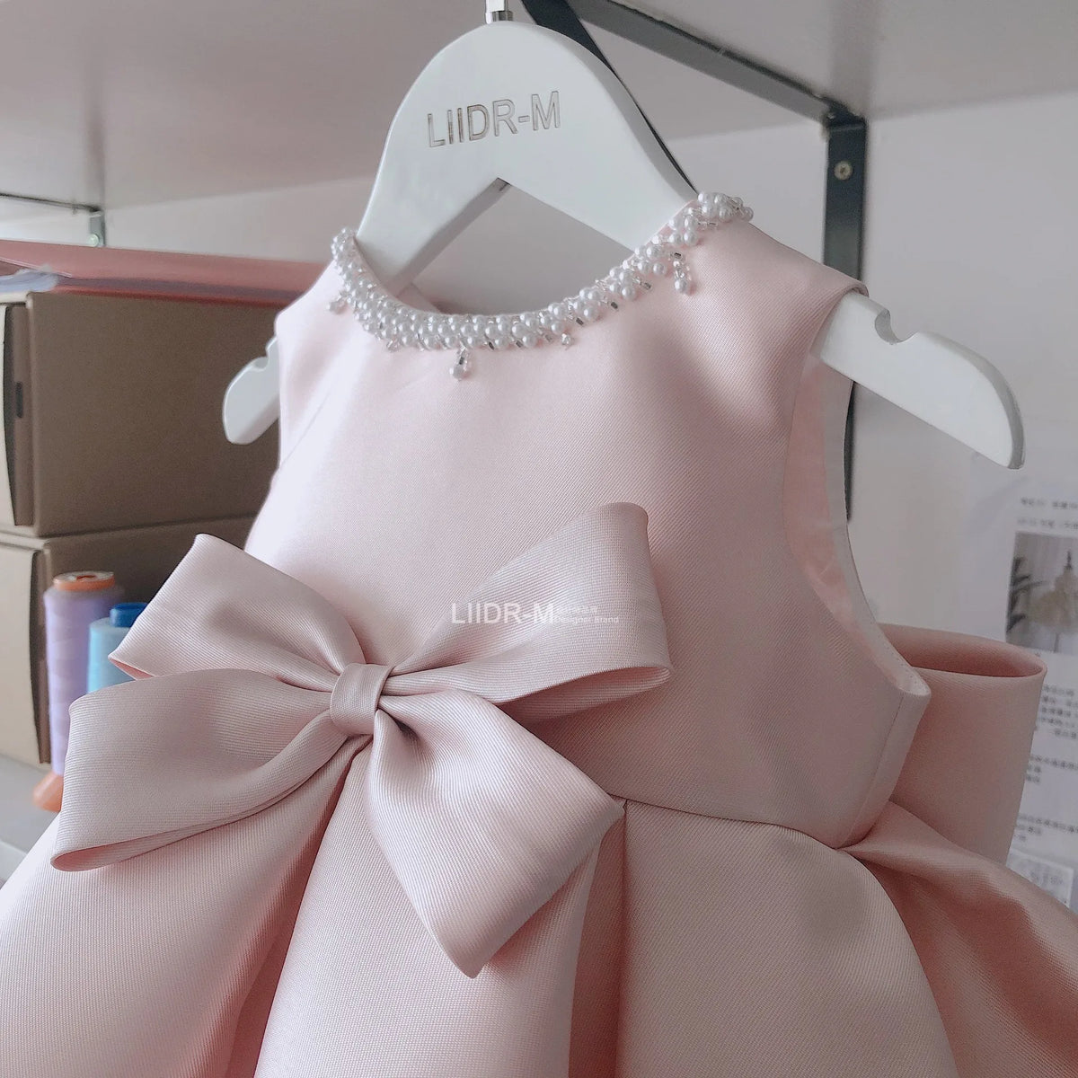 baby pink special occasion dress with pearl neckline and large bow for infants