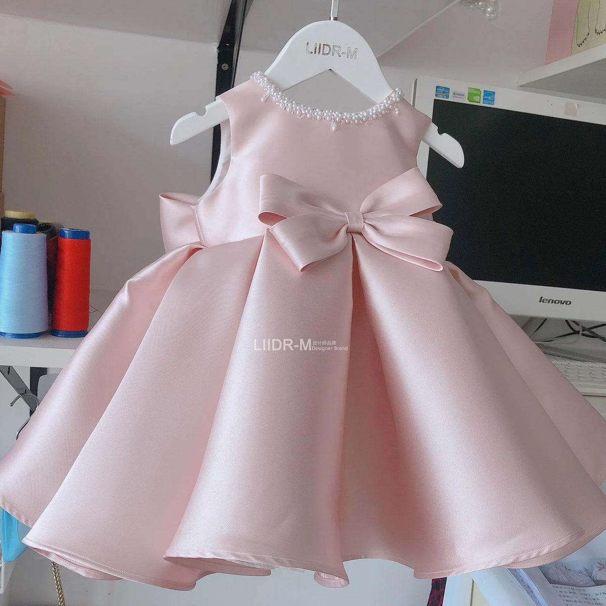 baby pink special occasion dress with pearl neckline and large bow detail