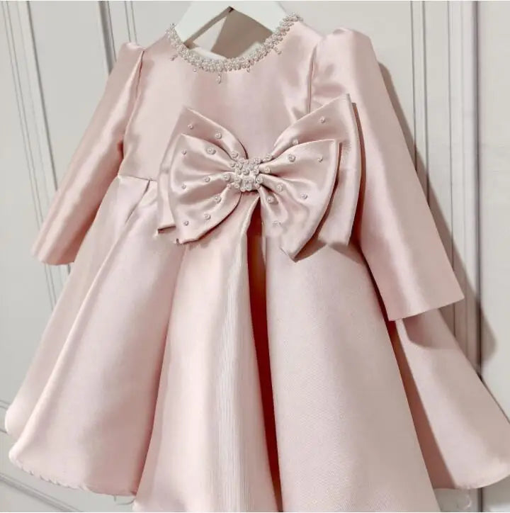 baby pink special occasion dress with long sleeves and embellished pearl bow detail