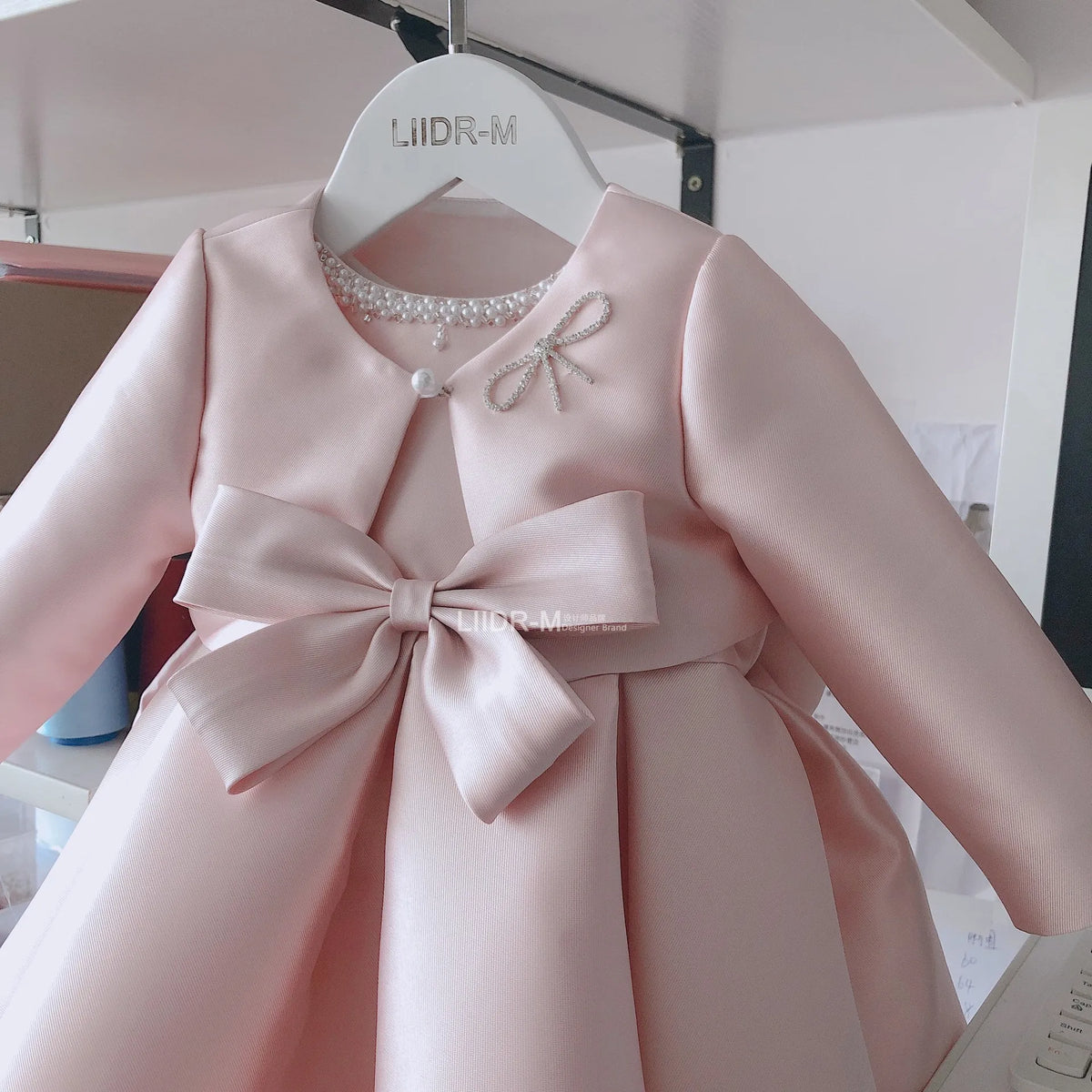 girls pink special occasion dress with pearl neckline and large bow for infants