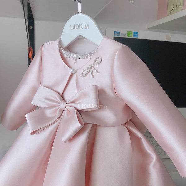 Baby pink special occasion dress for girls with long sleeves and large bow detail