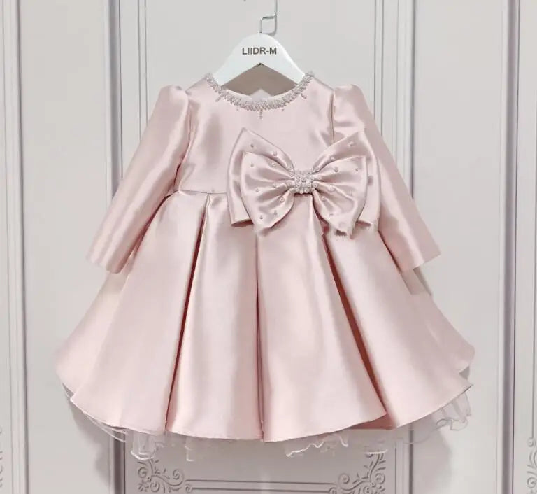 baby pink special occasion dress with long sleeves and large bow detail for toddler girls