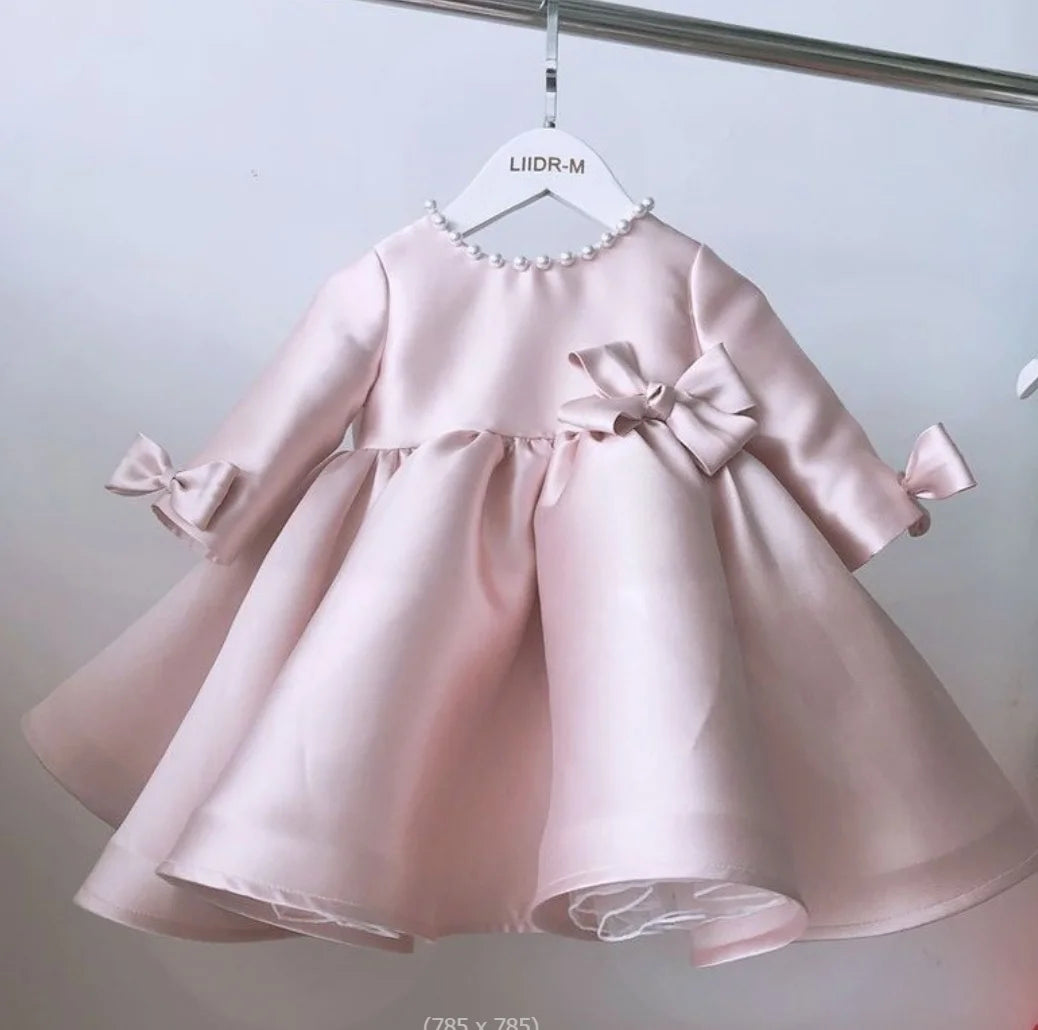 baby girls pale pink special occasion dress with pearl neckline and bow details on waist and sleeves