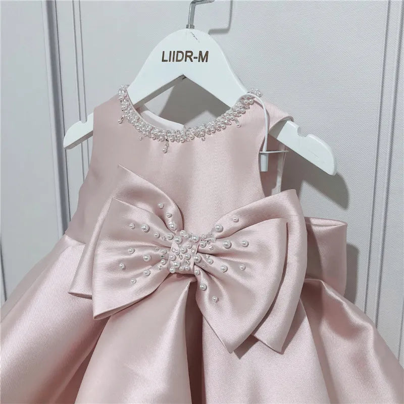 Baby girls pink special occasion dress with pearl embellished neckline and large bow