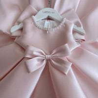baby pink special occasion dress with pearl neckline and large bow detail for infants