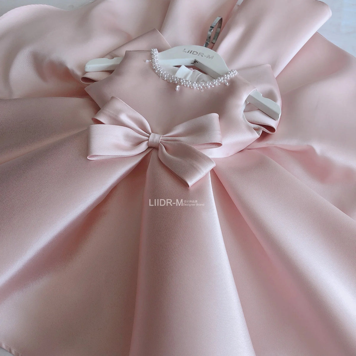 baby pink special occasion dress with neckline and large bow for infants