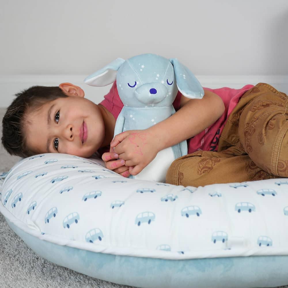 Boy hugging blue plush stuffed animal dog with white star pattern and closed eyes