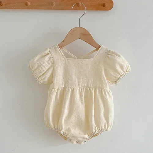 cream colored baby summer romper with puff sleeves and snap closures for easy diaper changes