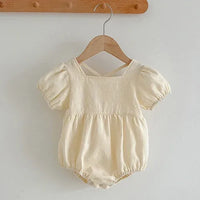 cream colored baby summer romper with puff sleeves and snap closures for easy diaper changes