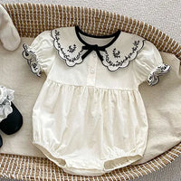 cream baby summer rompers with black embroidered scalloped collar and puff sleeves