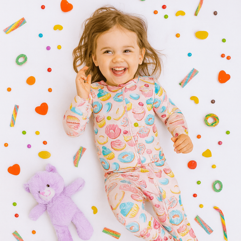 Child wearing a colorful pajama set with a teddy bear and candy-themed background