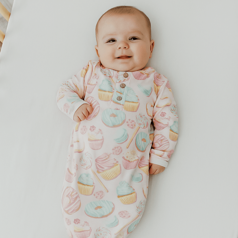 Baby wearing a colorful onesie with dessert patterns on a white background