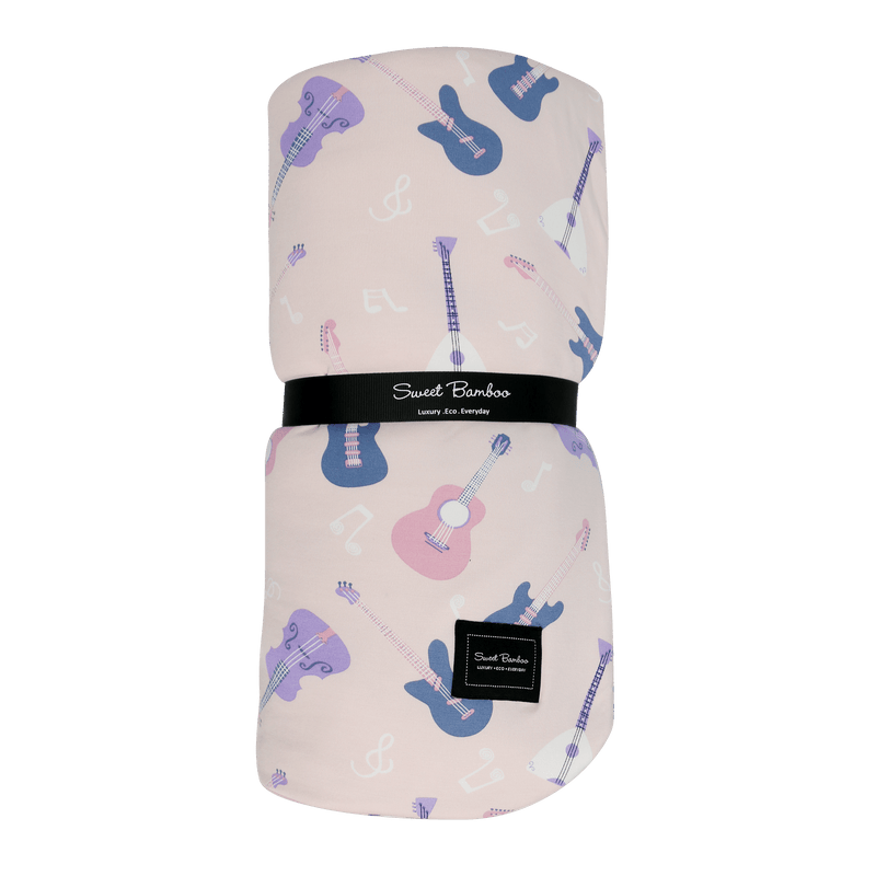 Pink Big Kid Cloud Blanket featuring colorful guitars and musical notes, rolled with a branded black band.