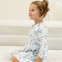 Side view of a young girl in a knee-length Watercolor Butterfly Swirly Girl Dress with long sleeves and butterfly print