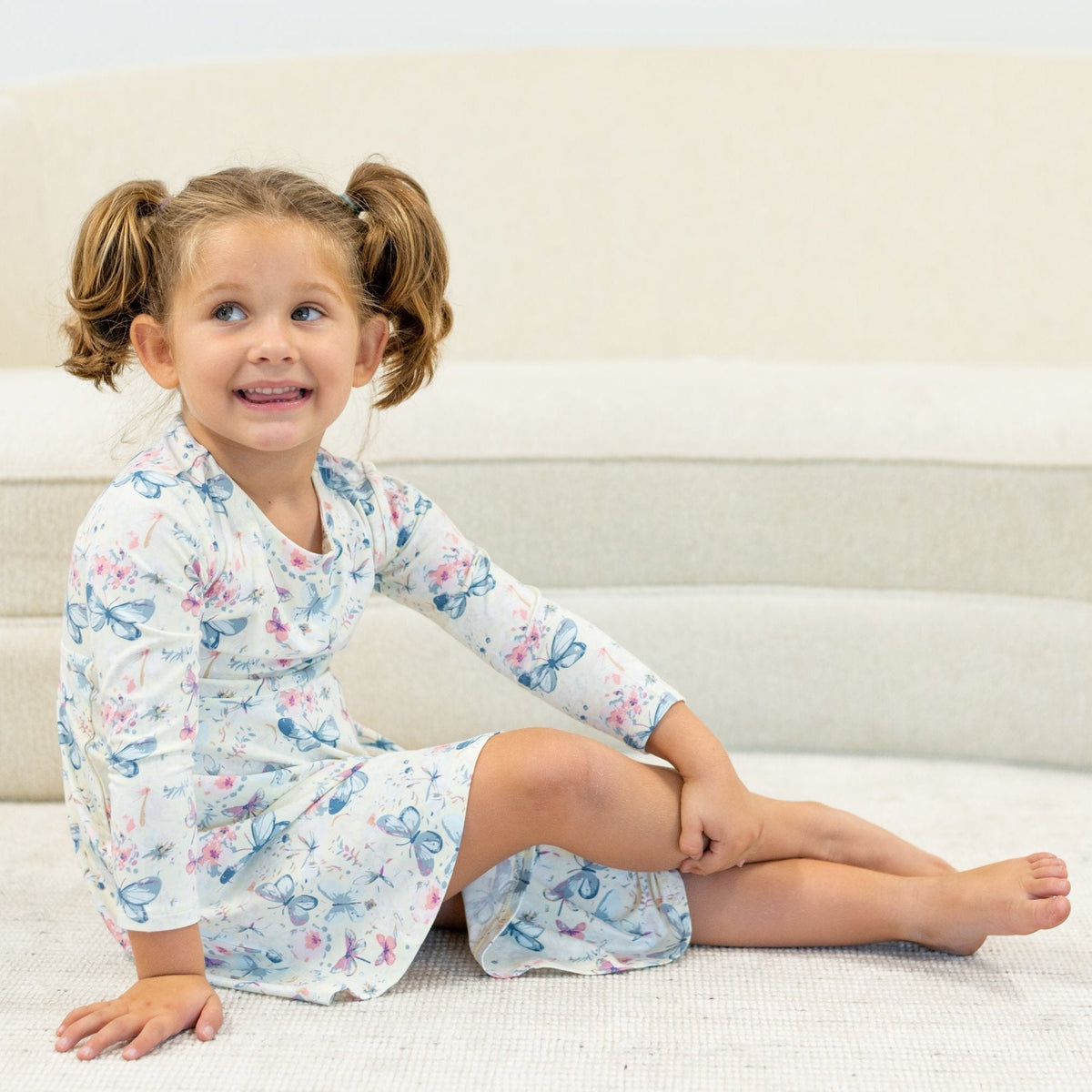 Little girl in Watercolor Butterfly Swirly Girl Dress with long sleeves, sitting on stairs.