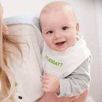 smiling baby wearing white and green taco baby bib set held by adult in gray and white clothing
