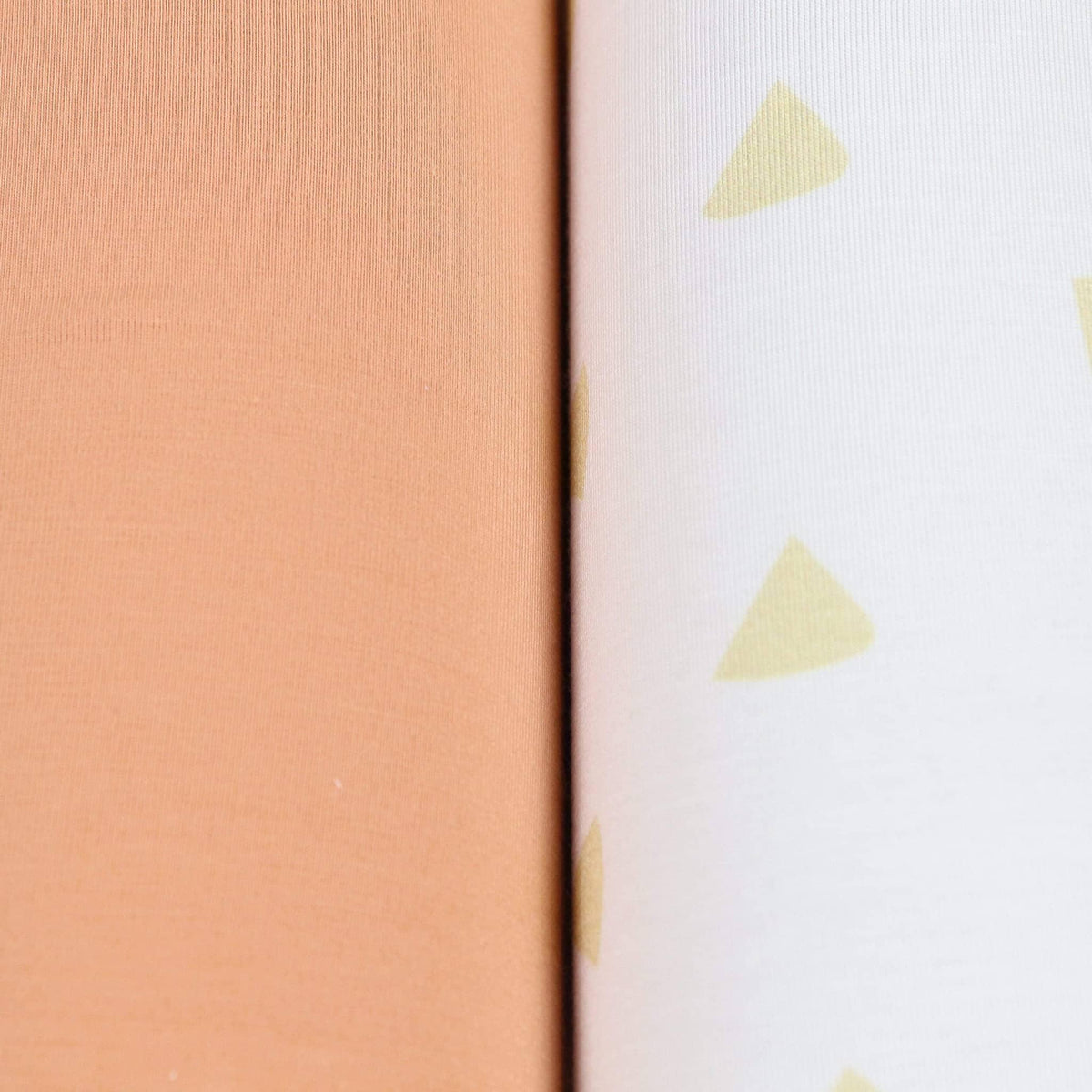 close-up of tan and terra cotta swaddle blankets for newborns showing solid and patterned fabric