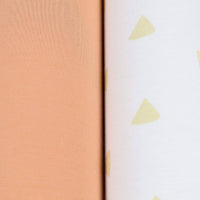 close-up of tan and terra cotta swaddle blankets for newborns showing solid and patterned fabric