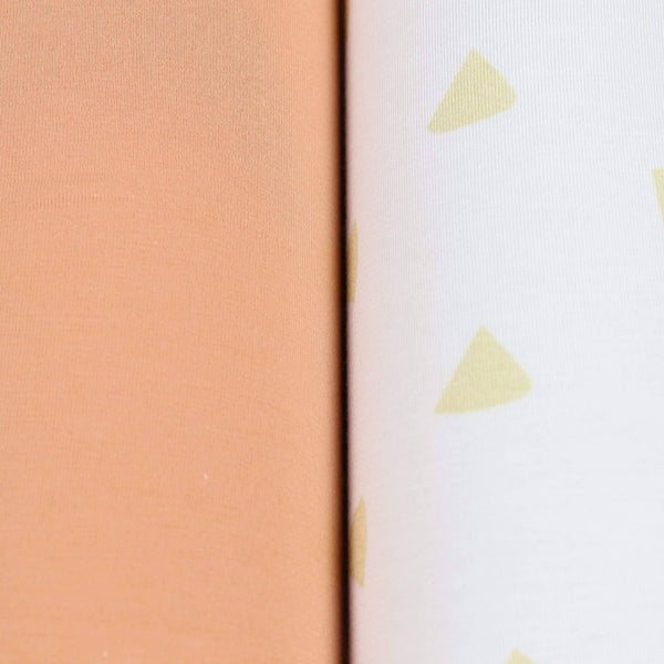 close-up of tan and terra cotta swaddle blankets for newborns showing solid and patterned fabric