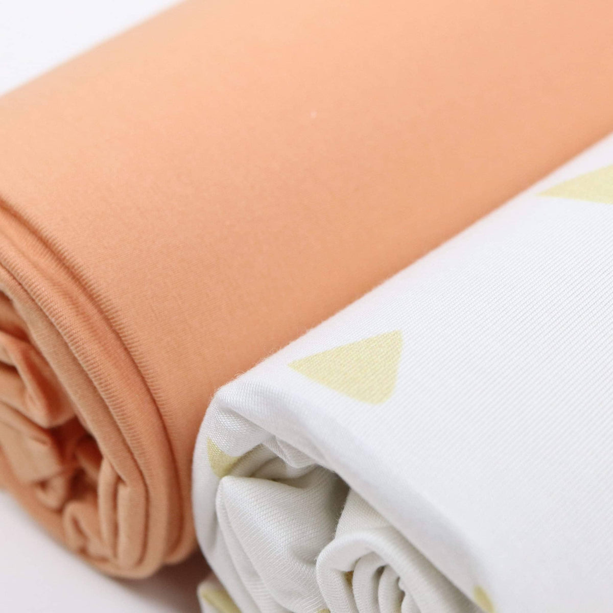 Close-up of rolled tan and terra cotta swaddle blankets for newborns by Goosewaddle