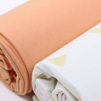 Close-up of rolled tan and terra cotta swaddle blankets for newborns by Goosewaddle