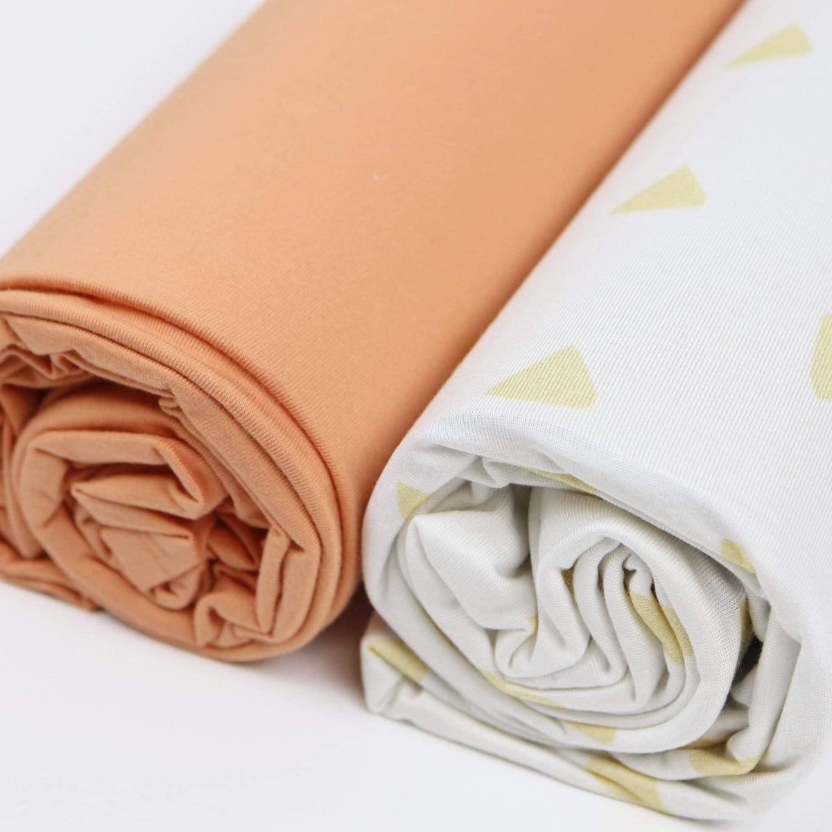Two rolled tan and terra cotta swaddle blankets for newborns from Goosewaddle
